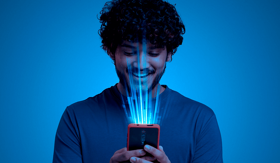Homem sorrindo com celular na mão. Artigo Marketing Empresarial| Blog Agência Magna.